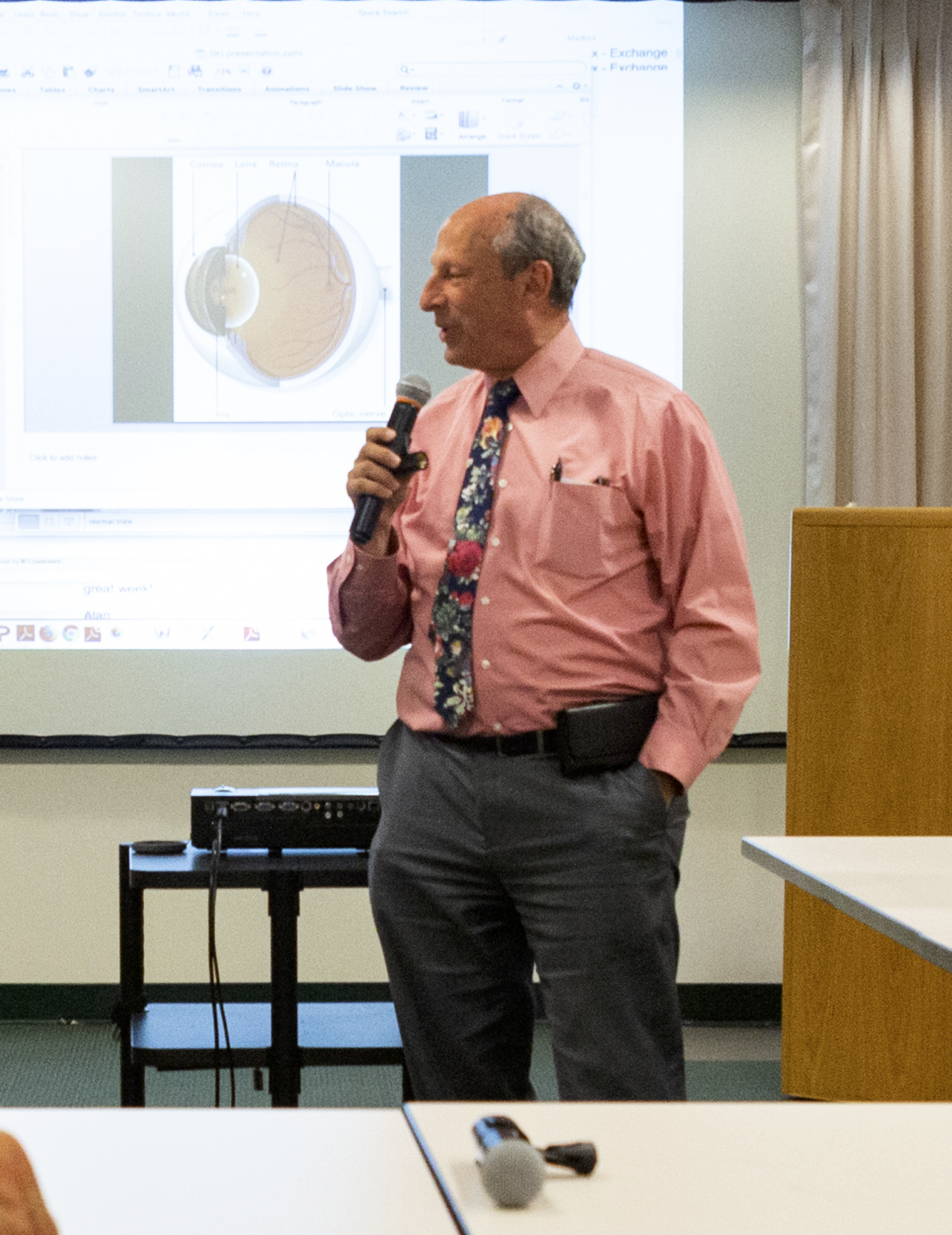 Dr. Fletcher speaking in front of a screen